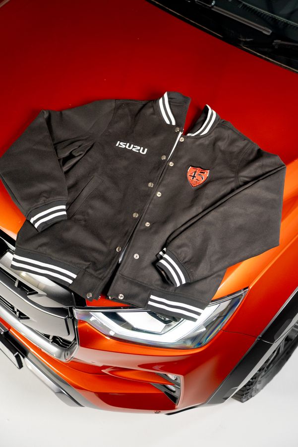 A black varsity jacket laid on the bonnet of an orange bakkie