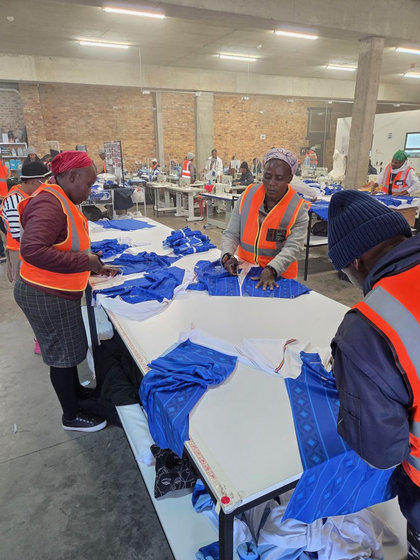 A team in hi-vis vests cutting blue printed fabric on the cutting table