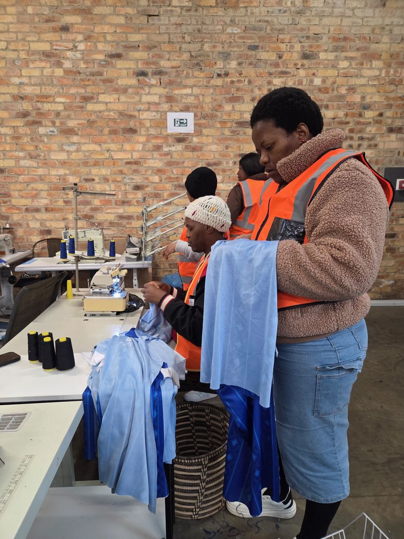 Staff in hi-vis vests checking finished blue garments