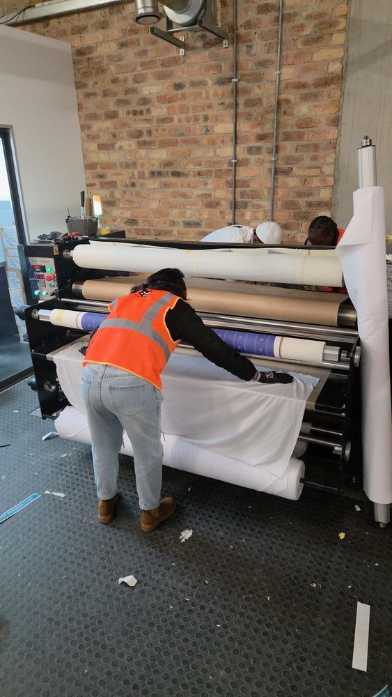 An operator in a hi-vis vest feeding a roll through the sublimation calender