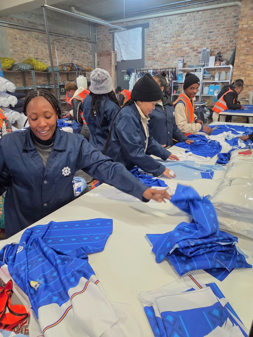 Machinists in CCS coats laying out blue printed panels at the cutting table