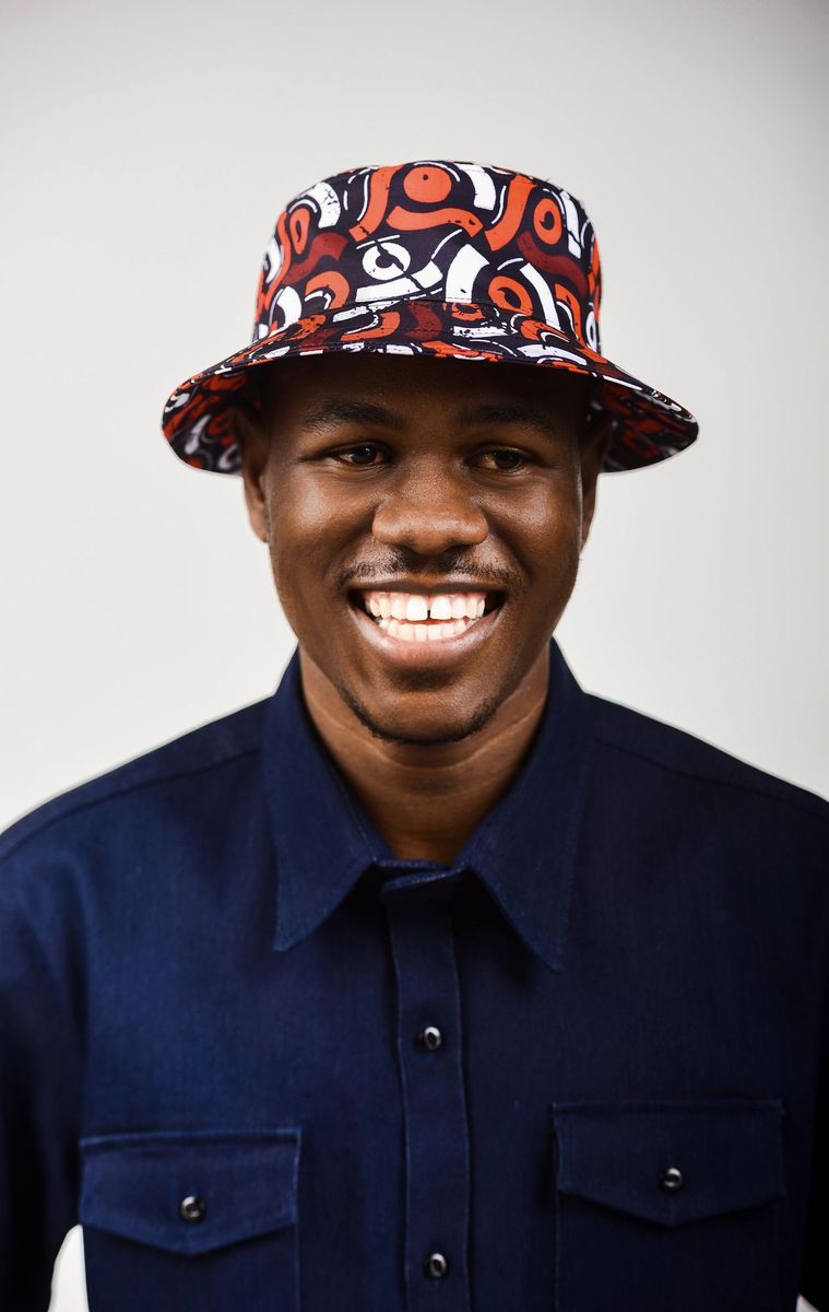 A smiling man in a red print bucket hat and navy shirt