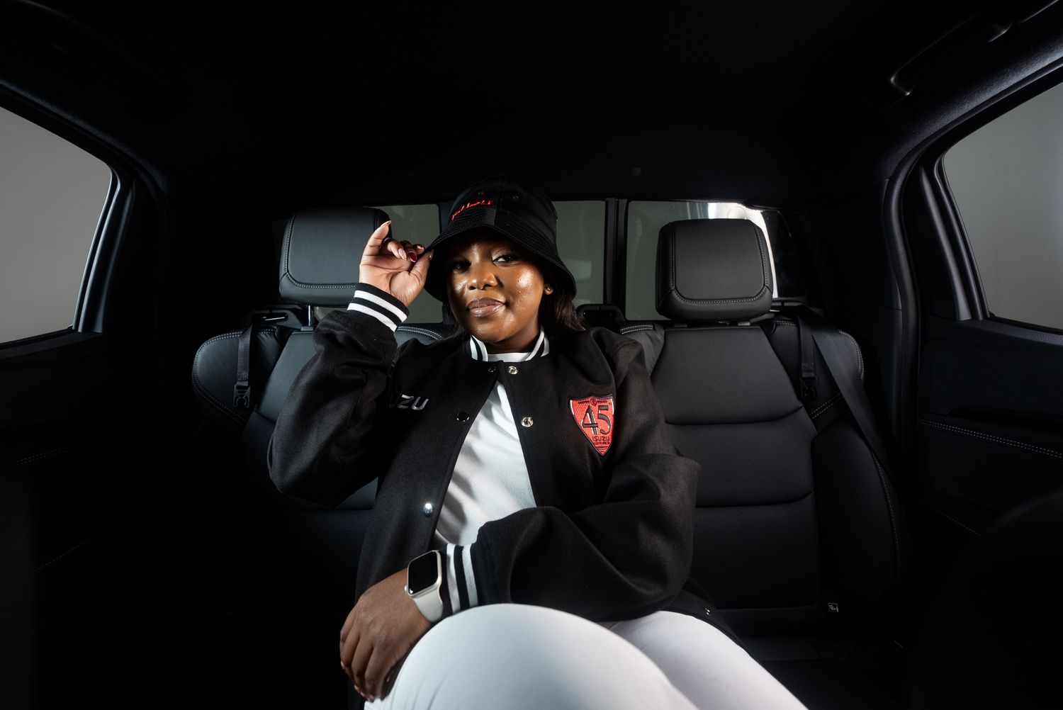 A woman in an Isuzu bucket hat and black bomber inside a bakkie cab