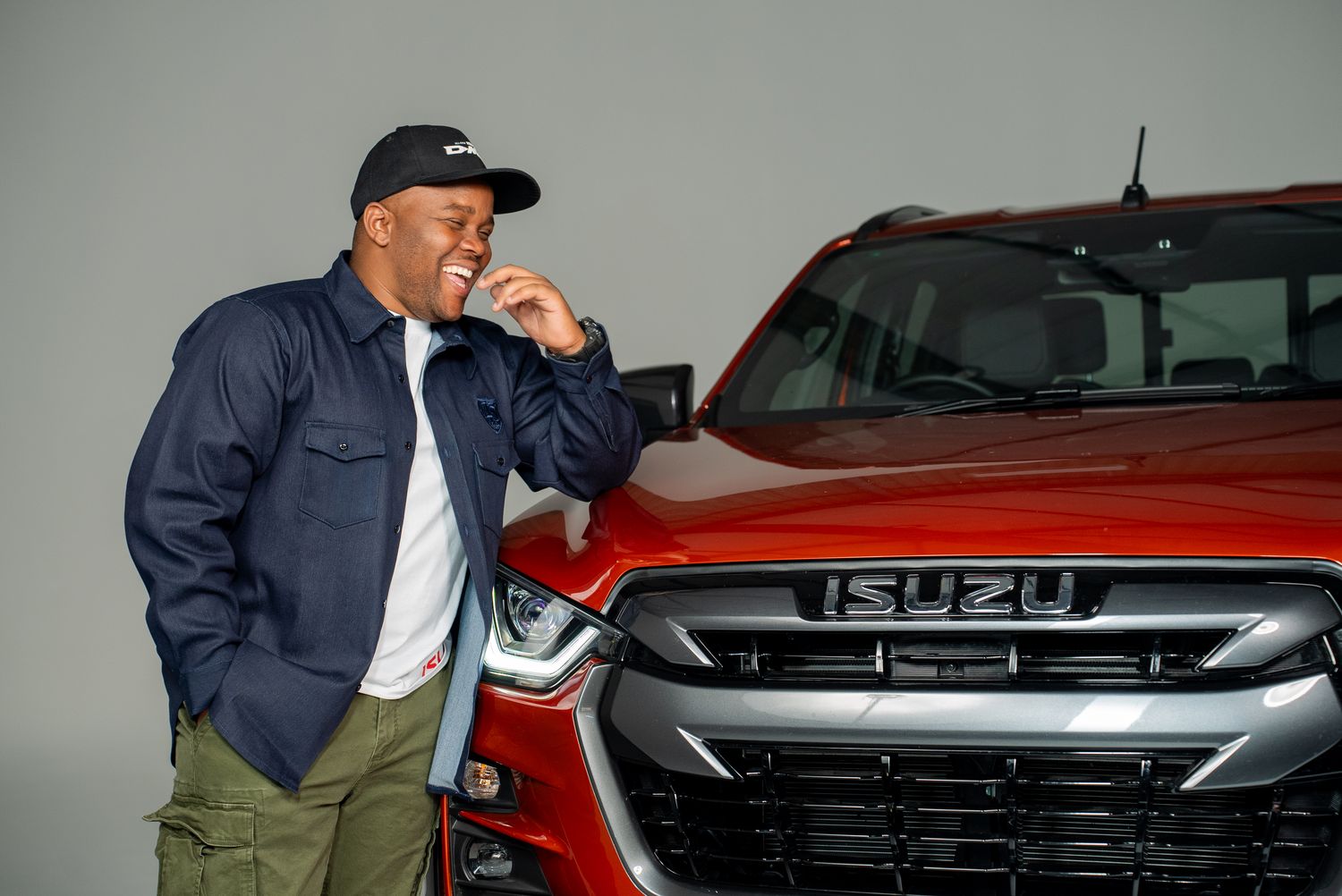 Two people in navy shirts leaning on an Isuzu D-Max grille