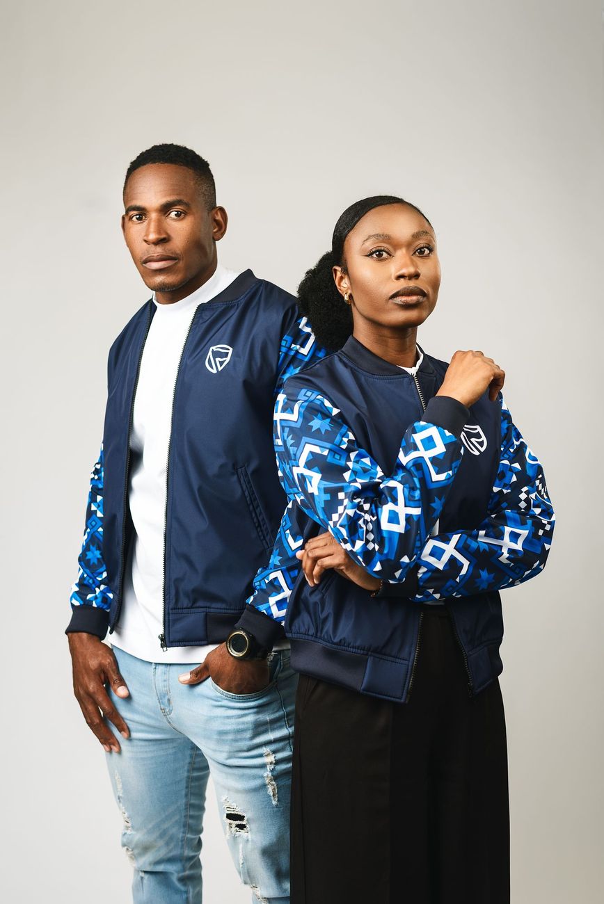 Two people in navy bomber jackets with blue geometric print sleeves