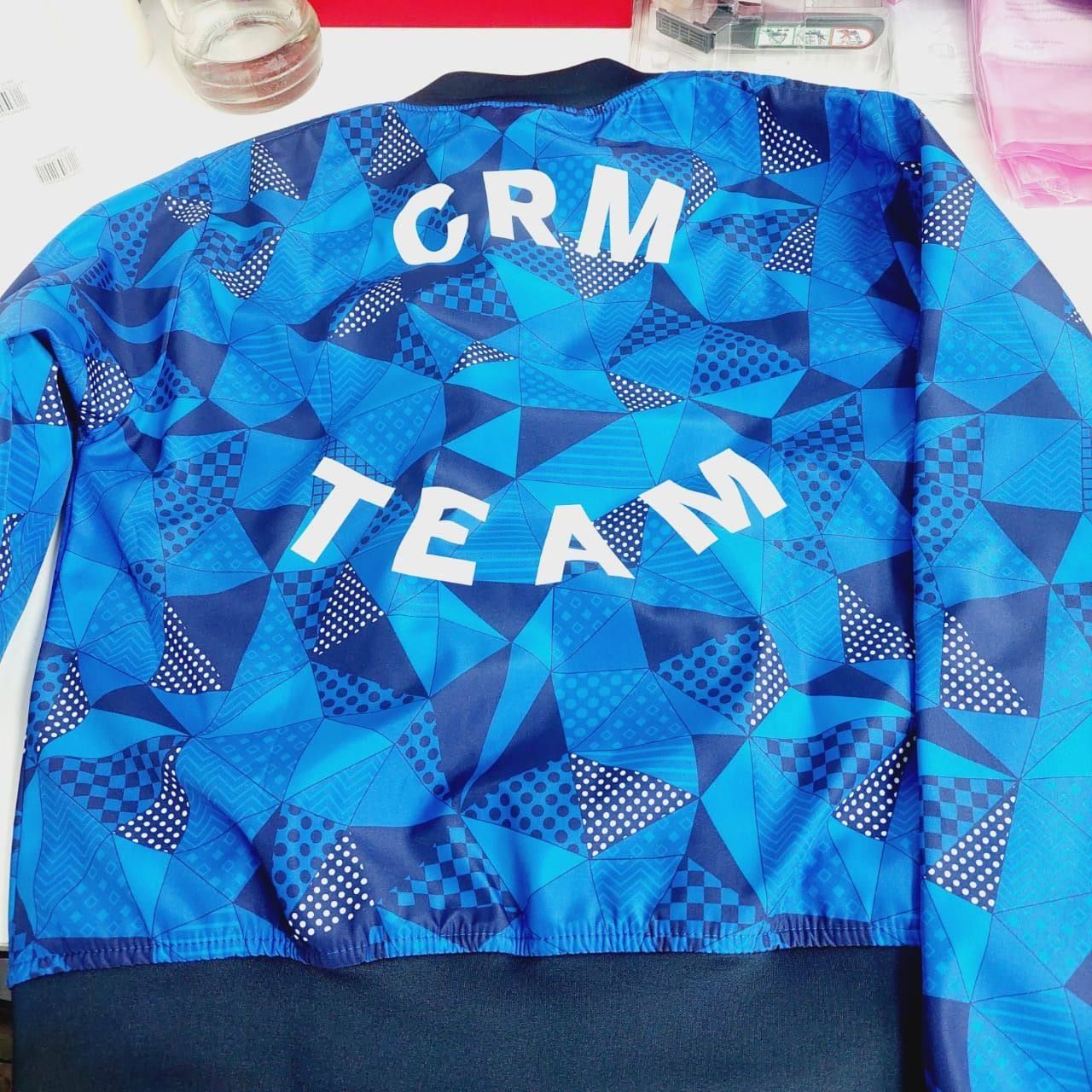 The back of a blue geometric print jacket reading CRM TEAM