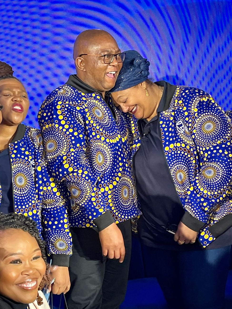 Staff at an event wearing blue and yellow mandala print jackets